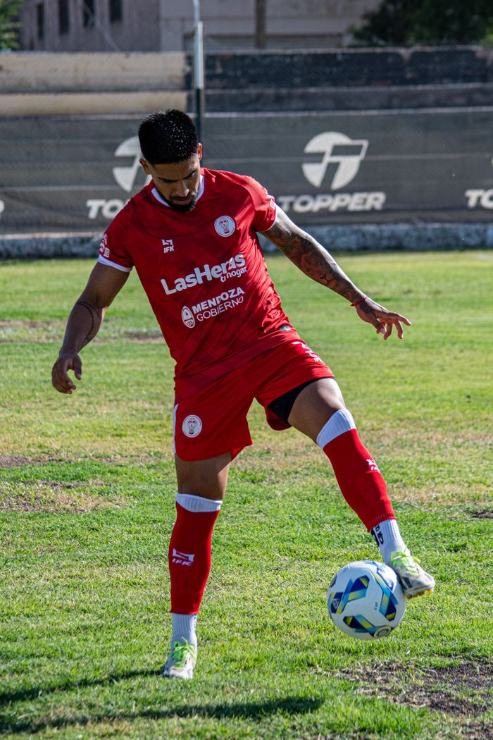 Soccer player practicing ball control skills on a grassy field in bright daylight.