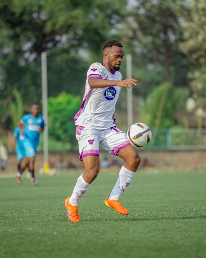 Dynamic shot of a football match capturing a player controlling the ball on a grassy field.